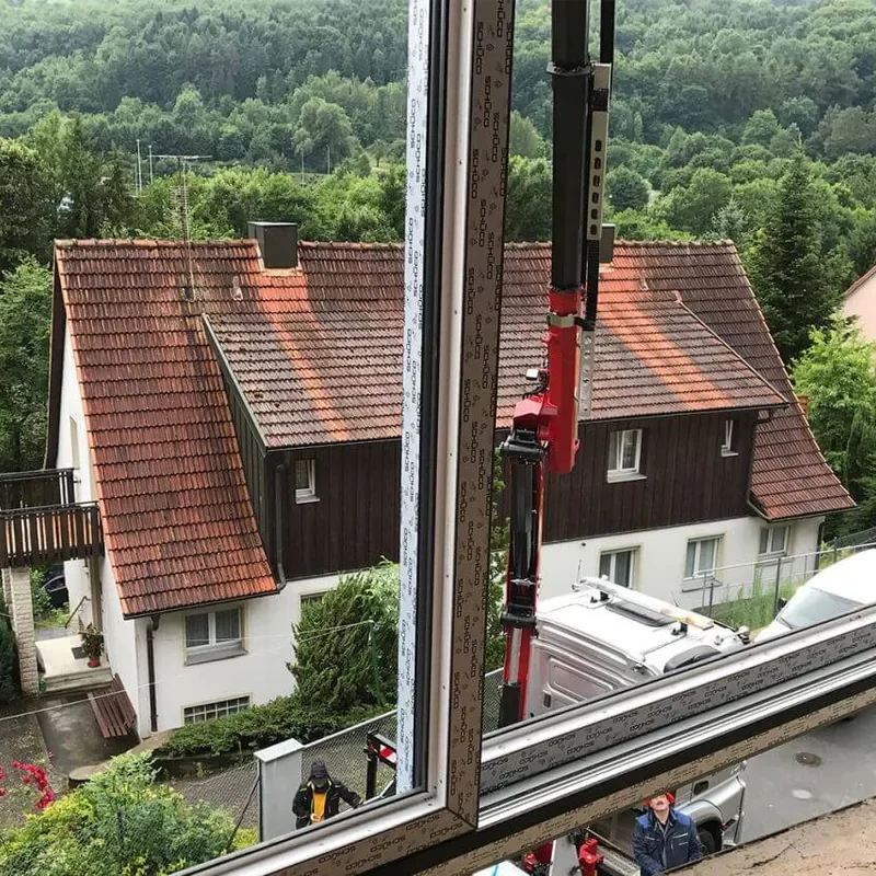 Einbau eines Schüco Fensters mit Blick auf ein Haus und grüne Landschaft durch NORTA. Präzise Montage für beste Isolierung.
