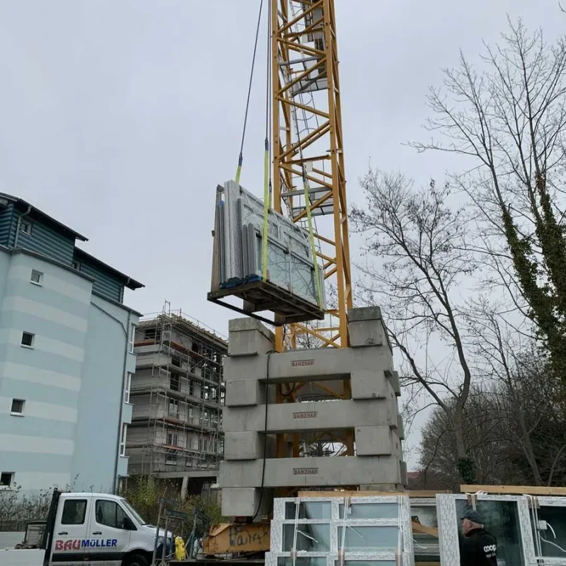 Fenster werden an einer Baustelle mit einem Kran transportiert. NORTA sorgt für effiziente Logistik und sichere Montage.