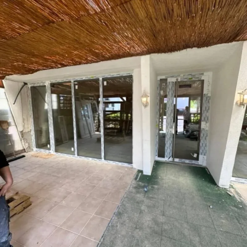 Veranda mit Glasschiebetür von NORTA, im Bau. Ideal für lichtdurchflutete Wohnbereiche mit hohem Wohnkomfort.